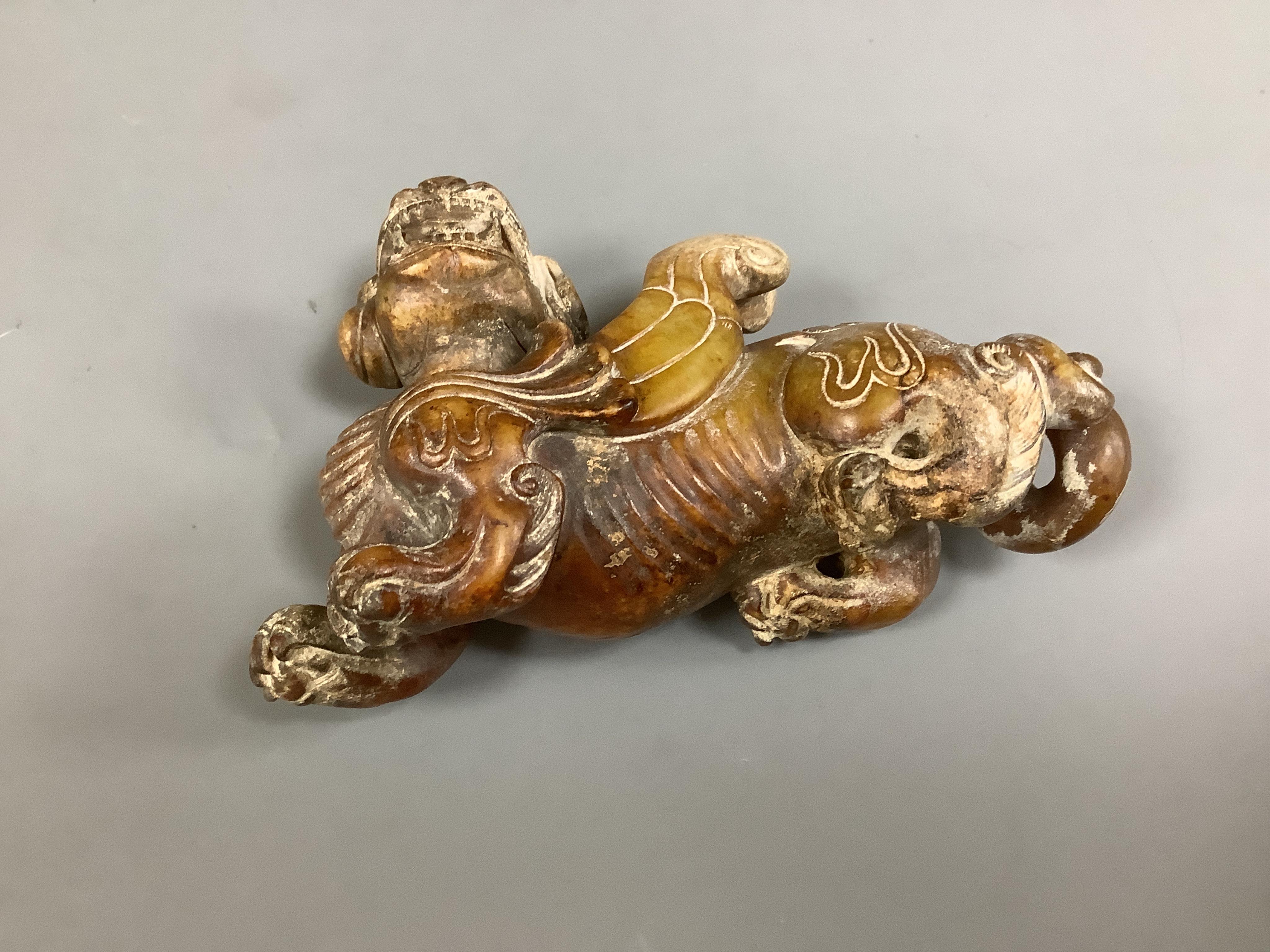 A Chinese archaistic pale celadon russet and burnt jade figure of a winged mythical beast, wood stand, mythical beast 12cm wide. Condition - carving good, stand good